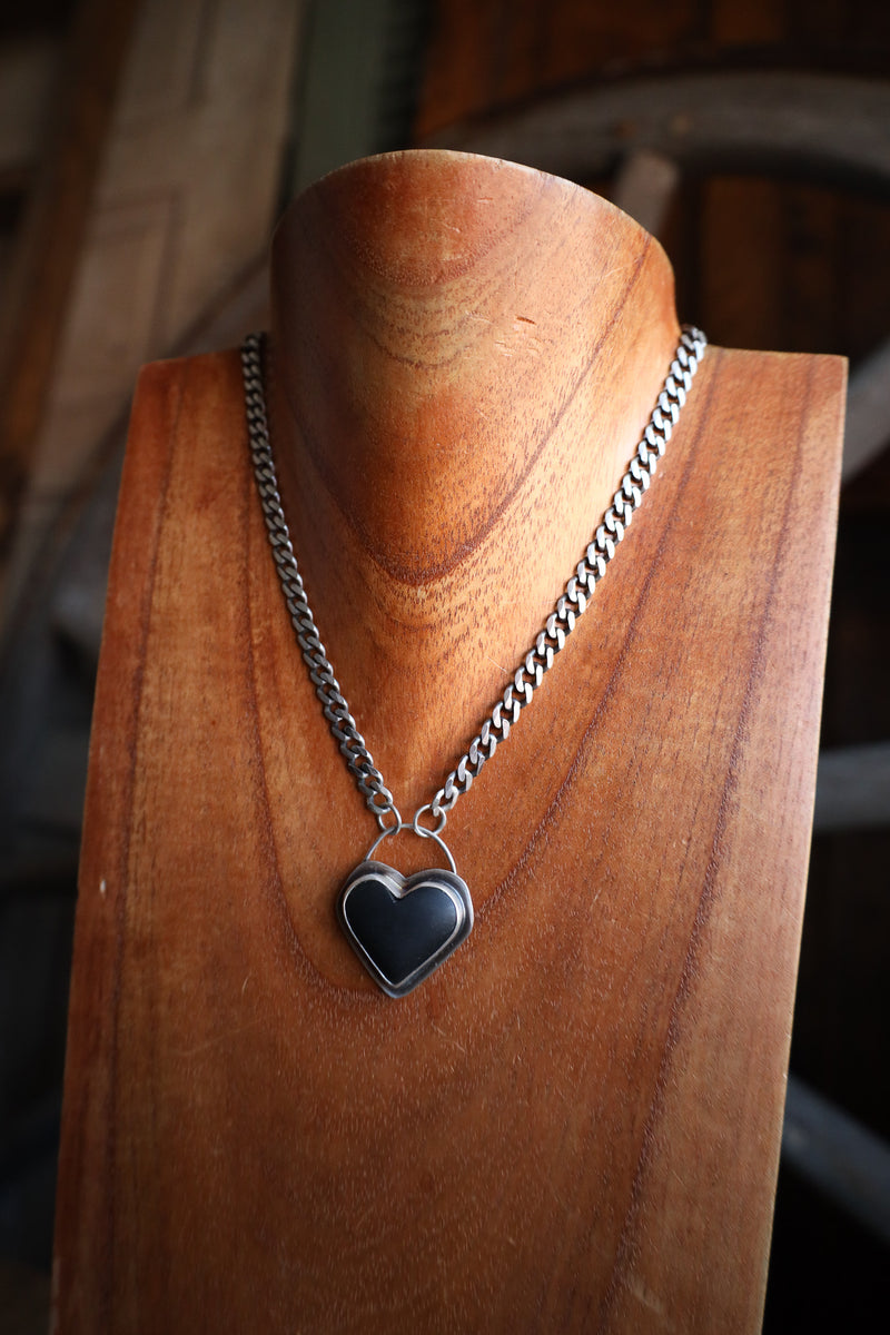 Necklace with a heart-shaped pendant on a wooden mannequin bust.
