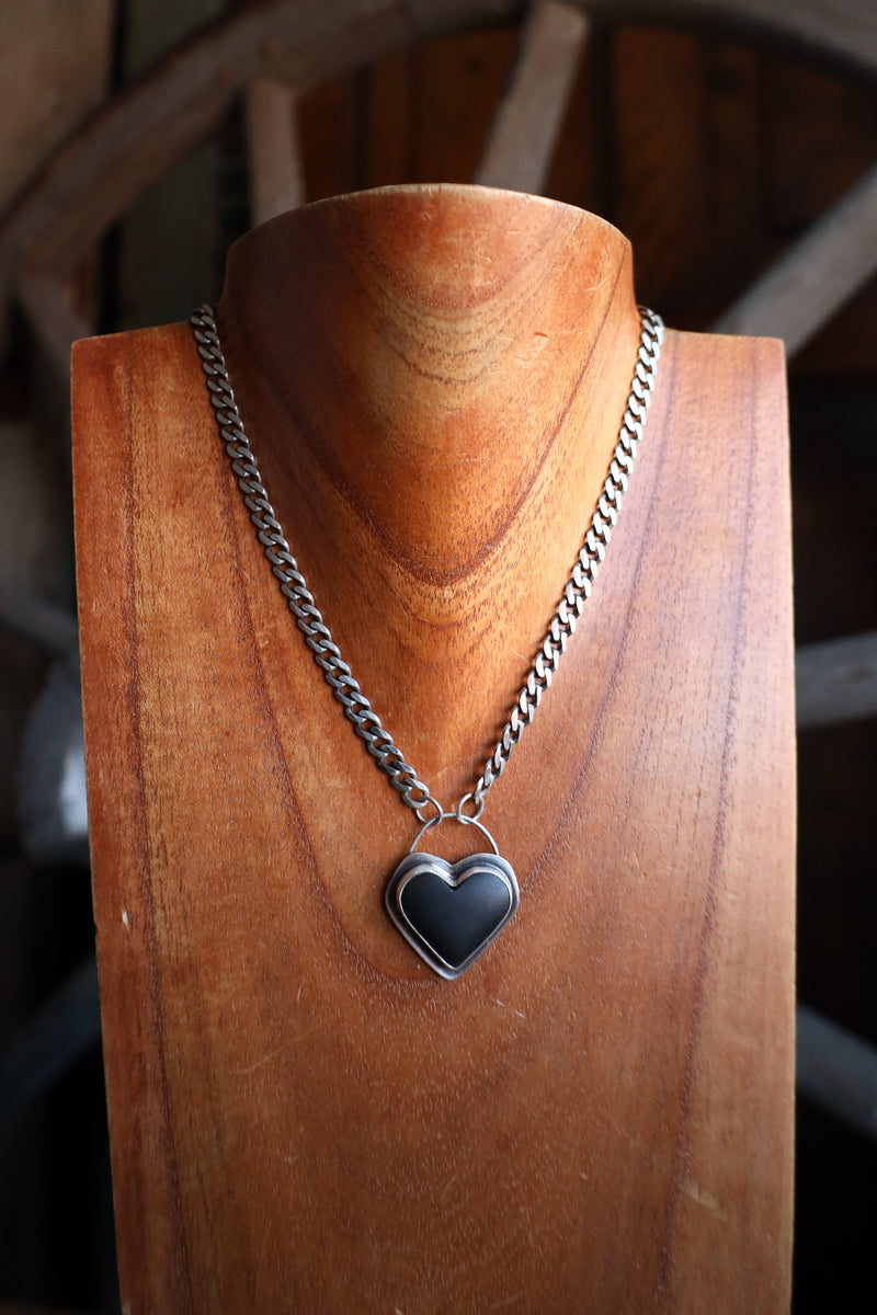 Necklace with a heart-shaped pendant on a wooden mannequin bust.
