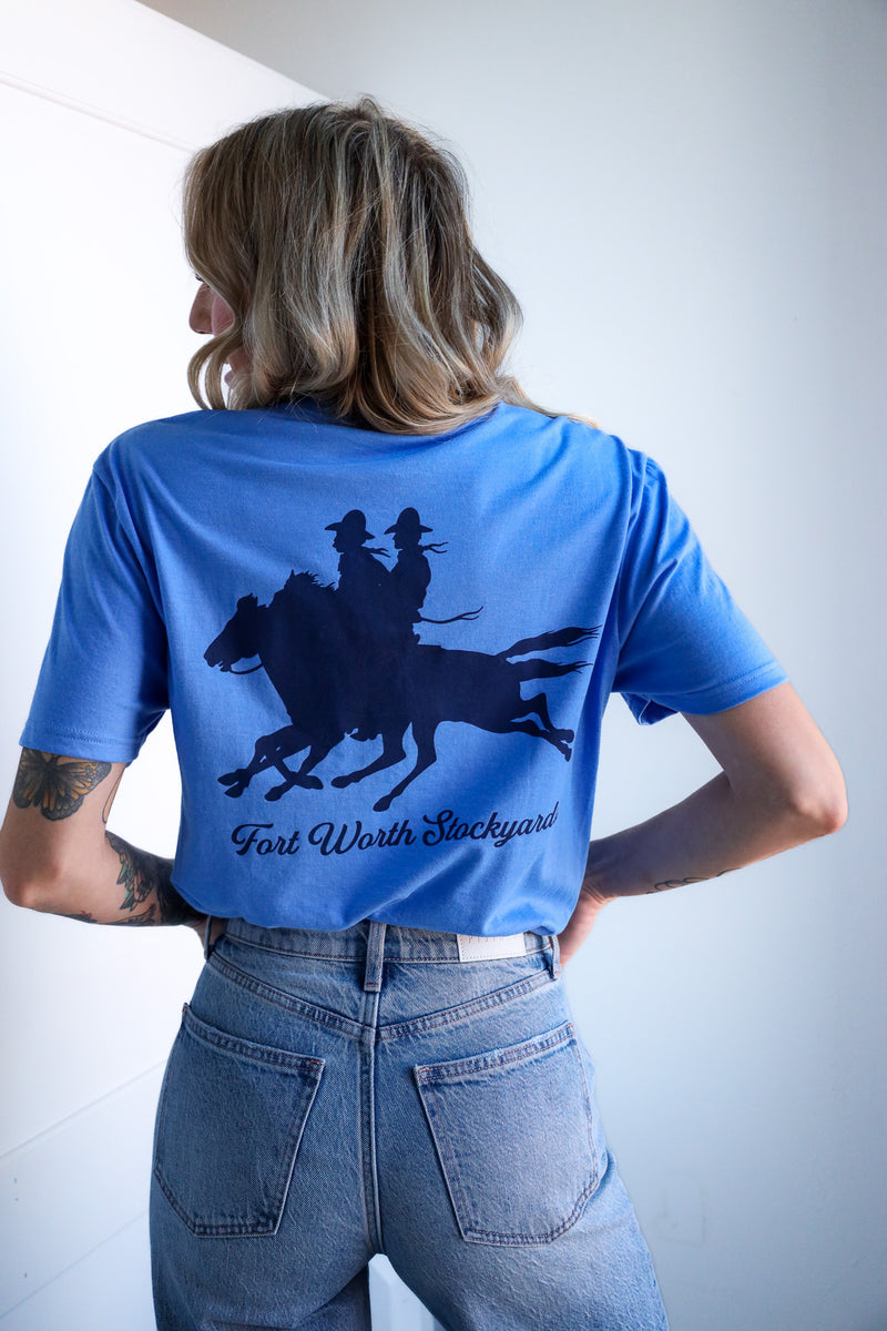 Person wearing a blue t-shirt with a graphic design on the back, standing against a plain background