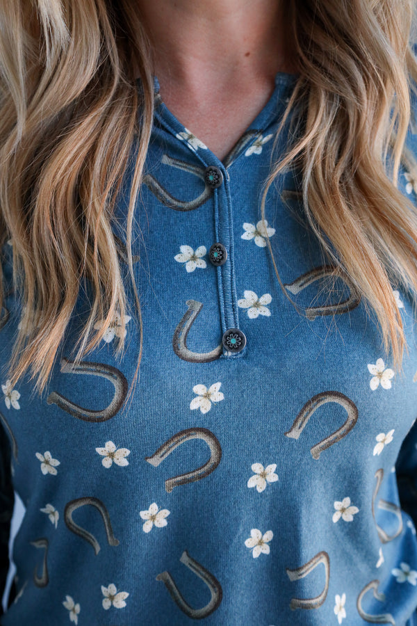 Close-up of a blue shirt with floral patterns and horseshoe designs.