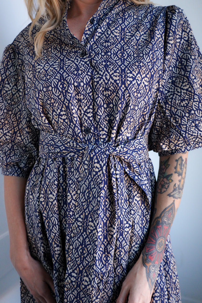 Person wearing a blue and white patterned dress with a plain background