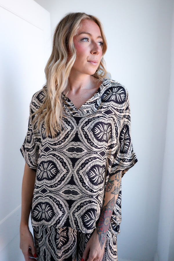Woman wearing a patterned dress against a plain background