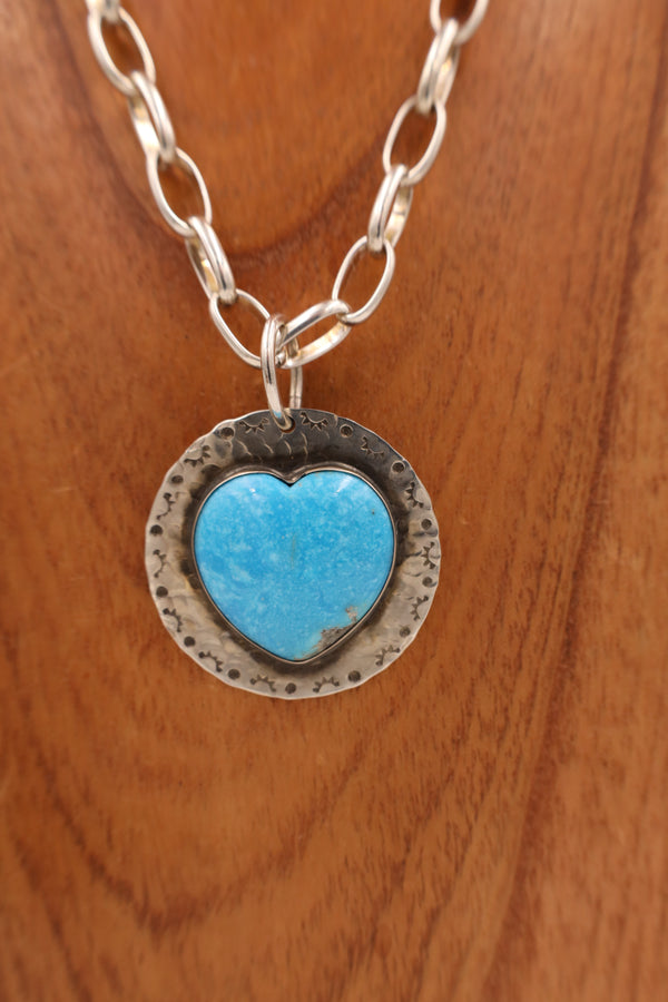 This large pendant handmade by Texas native Richard Schmidt highlights the multifaceted nature of the Turquoise stone. Features a large slab of genuine Turquoise plated on textured Sterling Silver. Though simple in its design, this spectacular pendant is not understated in its beauty!