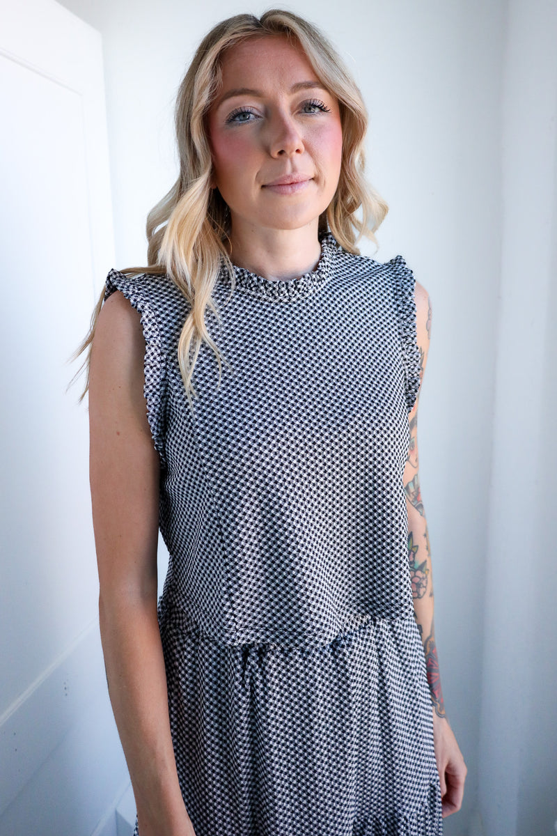 Woman wearing a sleeveless patterned dress against a white background