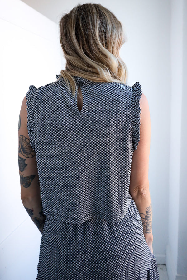 Person wearing a sleeveless patterned dress against a white background