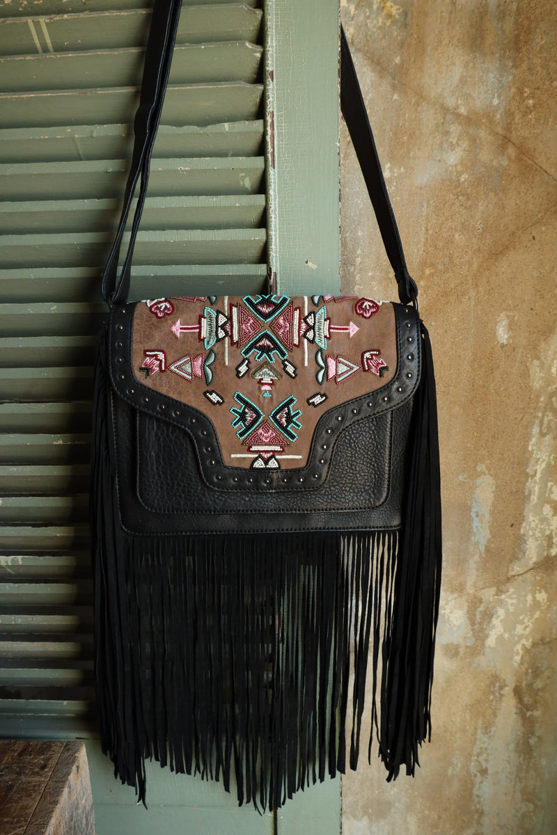 Experience the ultimate in boho-chic with the Old Gringo Mojo Black Bag. Made of luxurious black leather, this crossbody purse features a stunning tribal pattern beaded brown leather flap, embellished with studs and black fringe. A magnet closure, back zipper compartment, and multiple inside pockets make it both stylish and functional. Elevate your outfit with this statement piece!