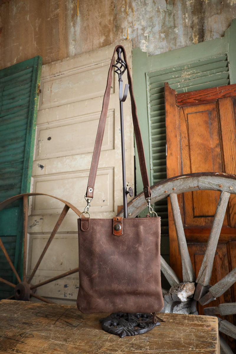 Brown leather tote bag on a wooden surface with rustic background