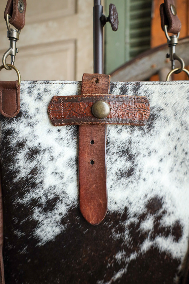 Close-up of a bag with cowhide leather and brown leather strap.