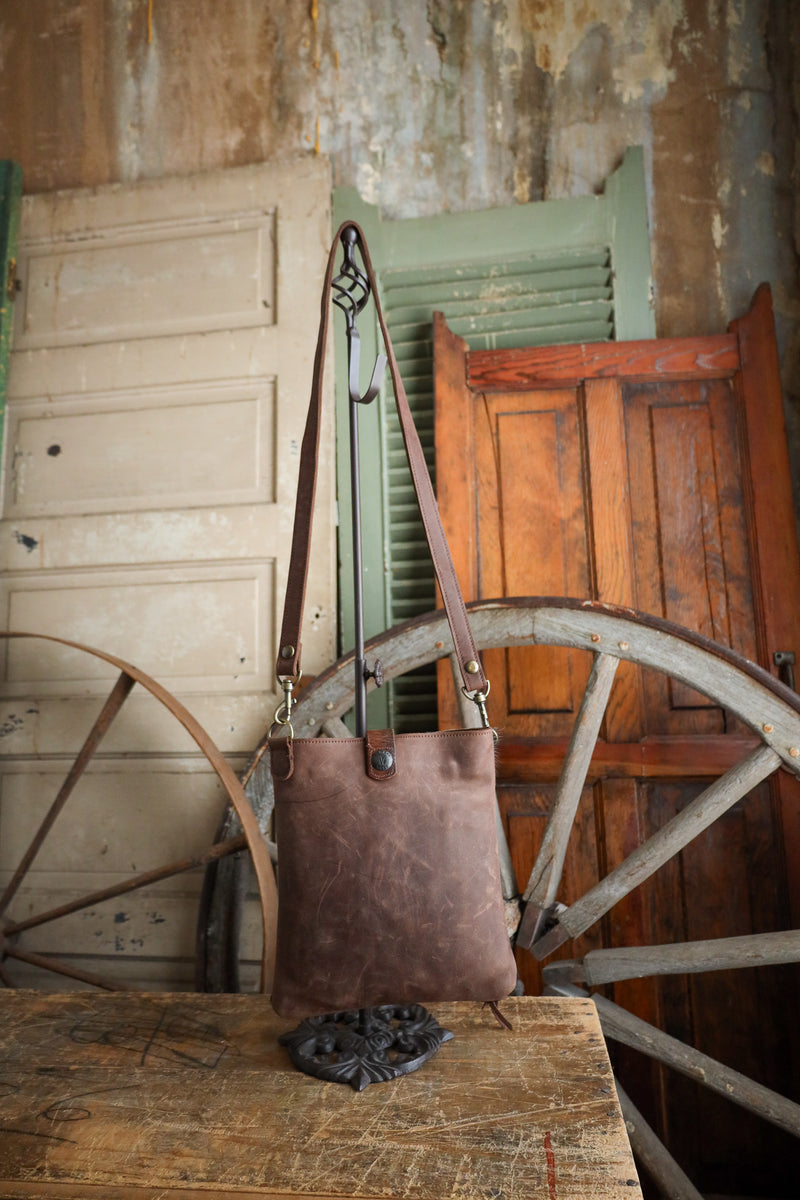Brown leather bag on a wooden table with rustic background