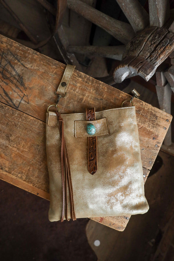 Brown leather pouch with turquoise stone on a rustic wooden surface