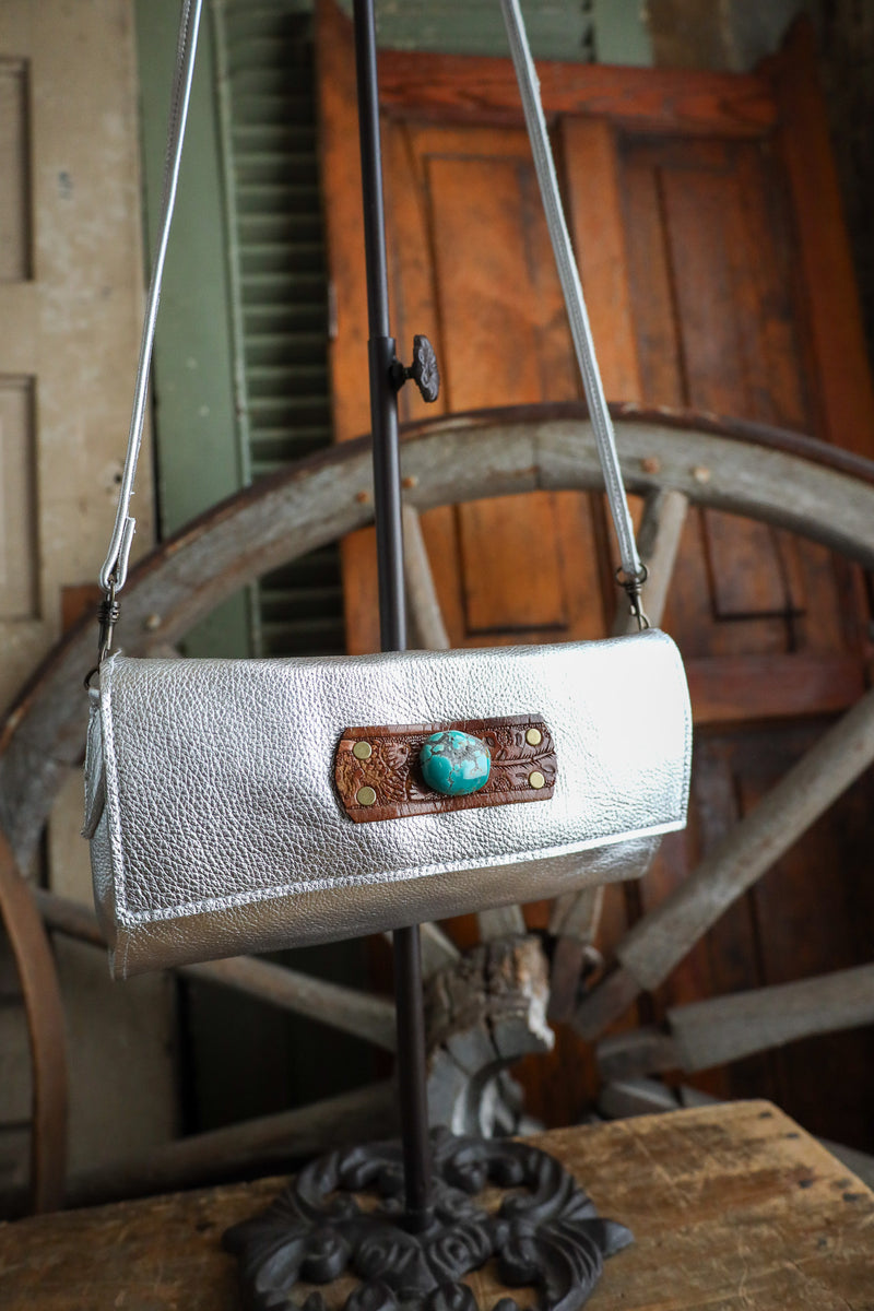 Silver handbag with a turquoise accent on a rustic wooden wheel background