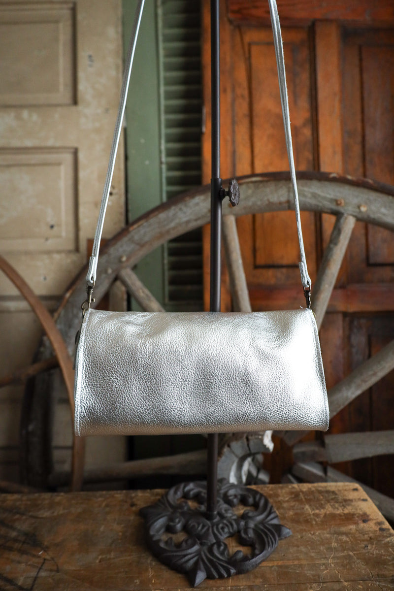 Silver handbag on a stand with a rustic wooden background