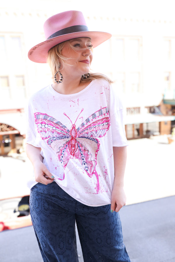 Woman wearing embroidered butterfly in vibrant colors on the crisp white fabric adds a playful touch tee, while the pink splatter detail brings a unique flair. Perfect for expressing your bold and lively personality.