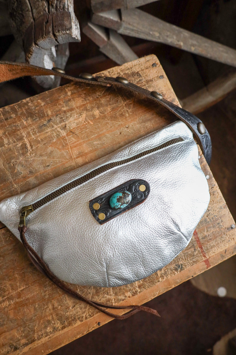 Silver leather bag with decorative patch on a wooden surface