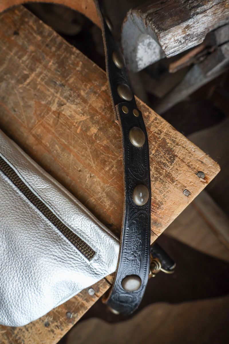 Close-up of a leather strap with metal studs on a rustic wooden surface