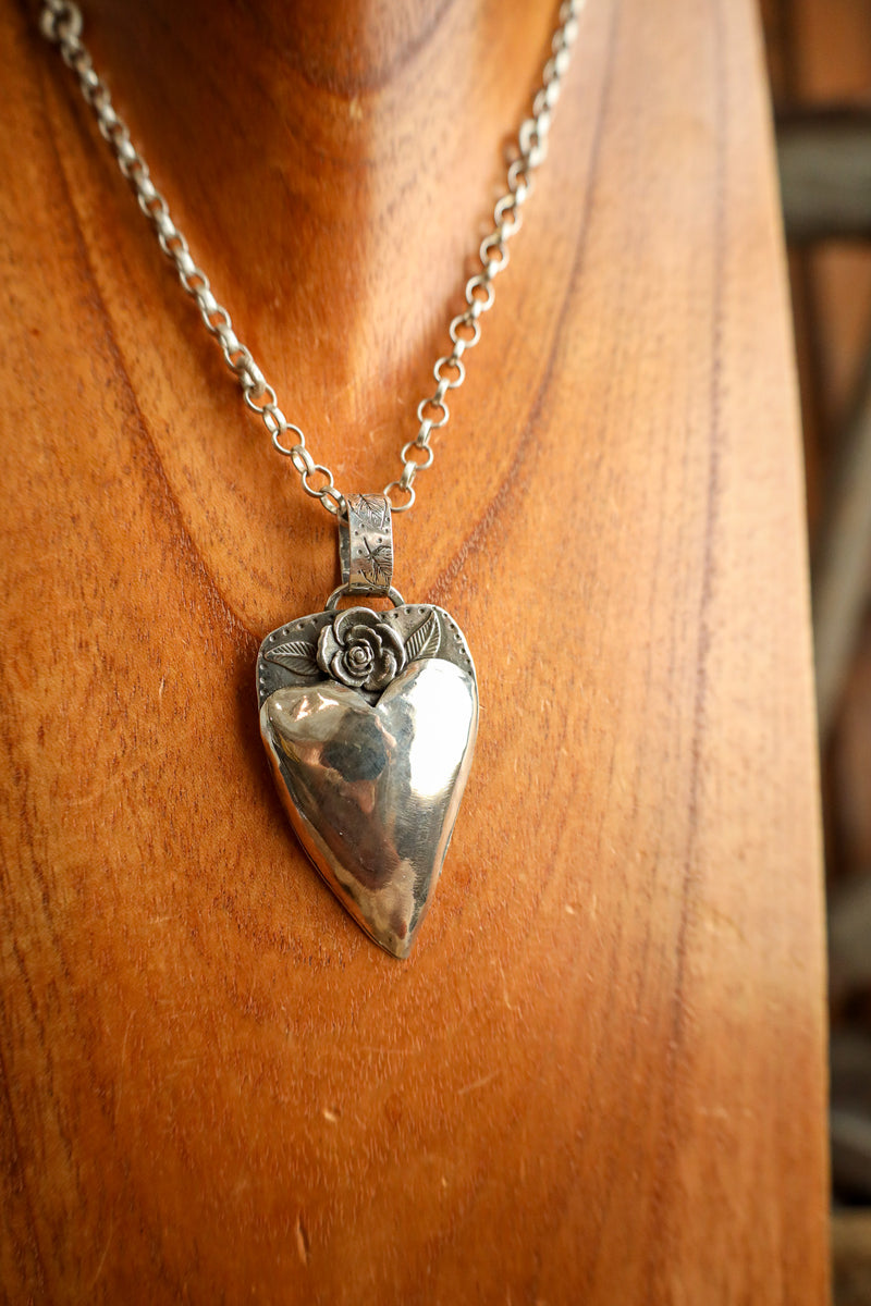 Silver heart-shaped pendant necklace on a wooden surface