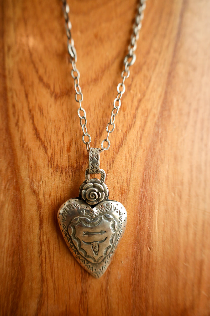 Silver heart-shaped pendant necklace on a wooden background