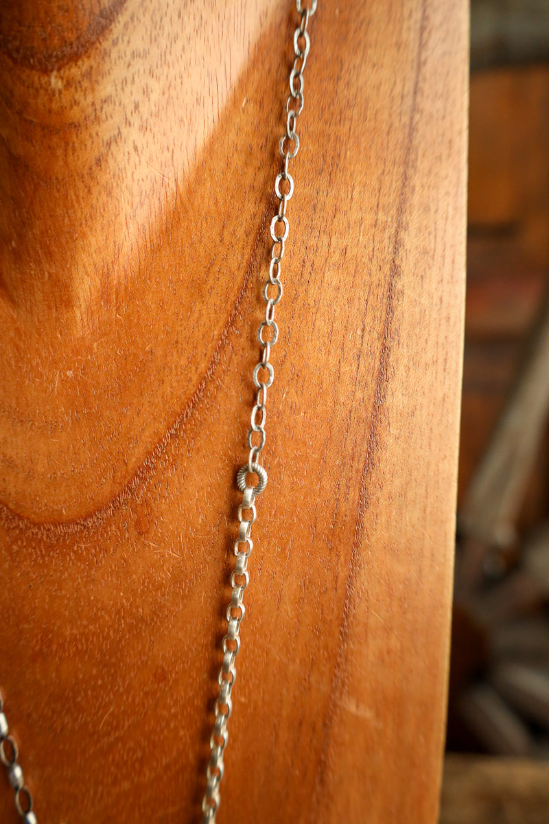 Silver chain hanging from a wooden surface