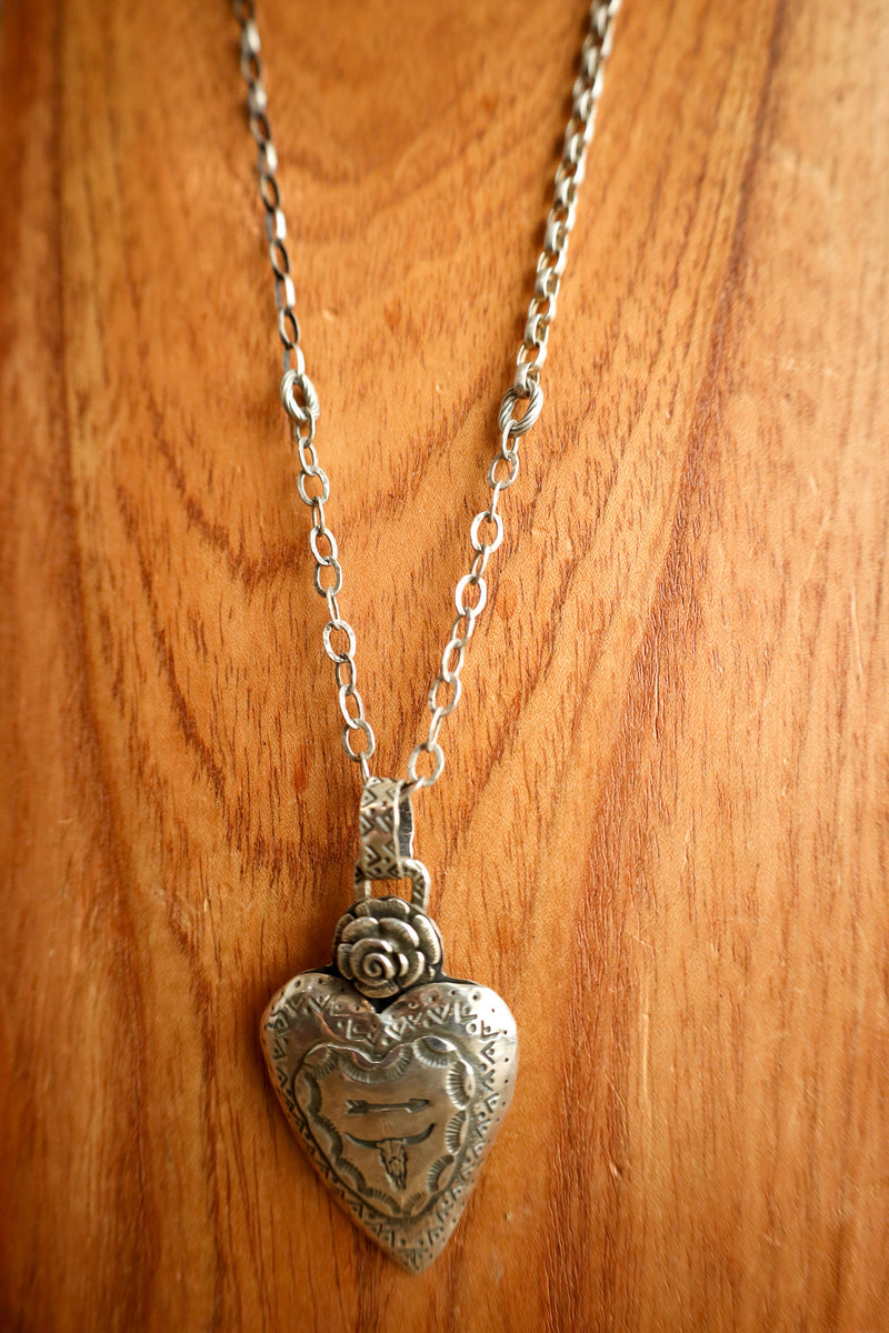 Silver heart-shaped pendant necklace on a wooden surface