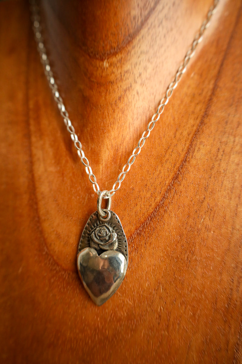 Silver heart-shaped pendant necklace on a wooden surface