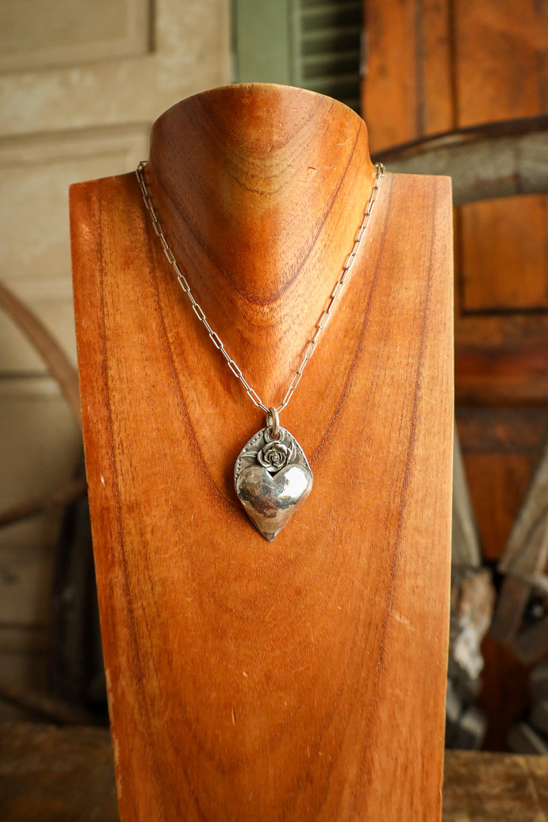 Silver necklace with a pendant on a wooden stand