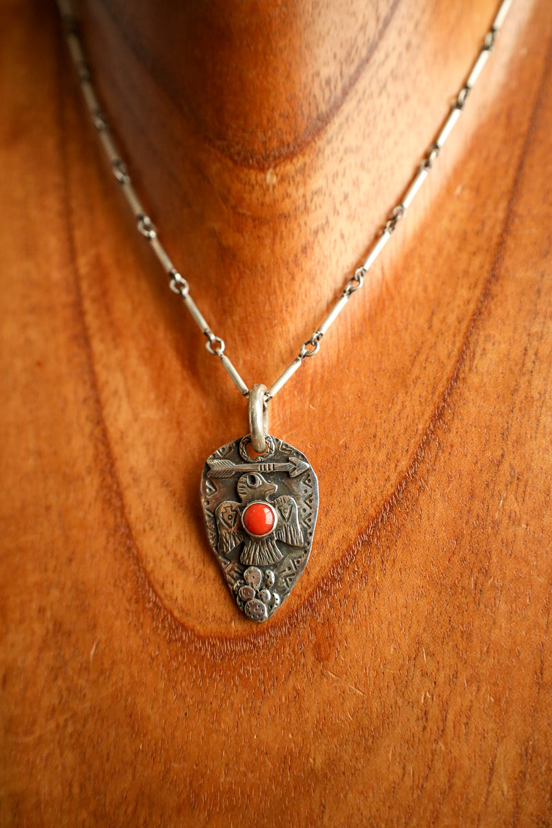 Silver necklace with a decorative pendant on a wooden surface