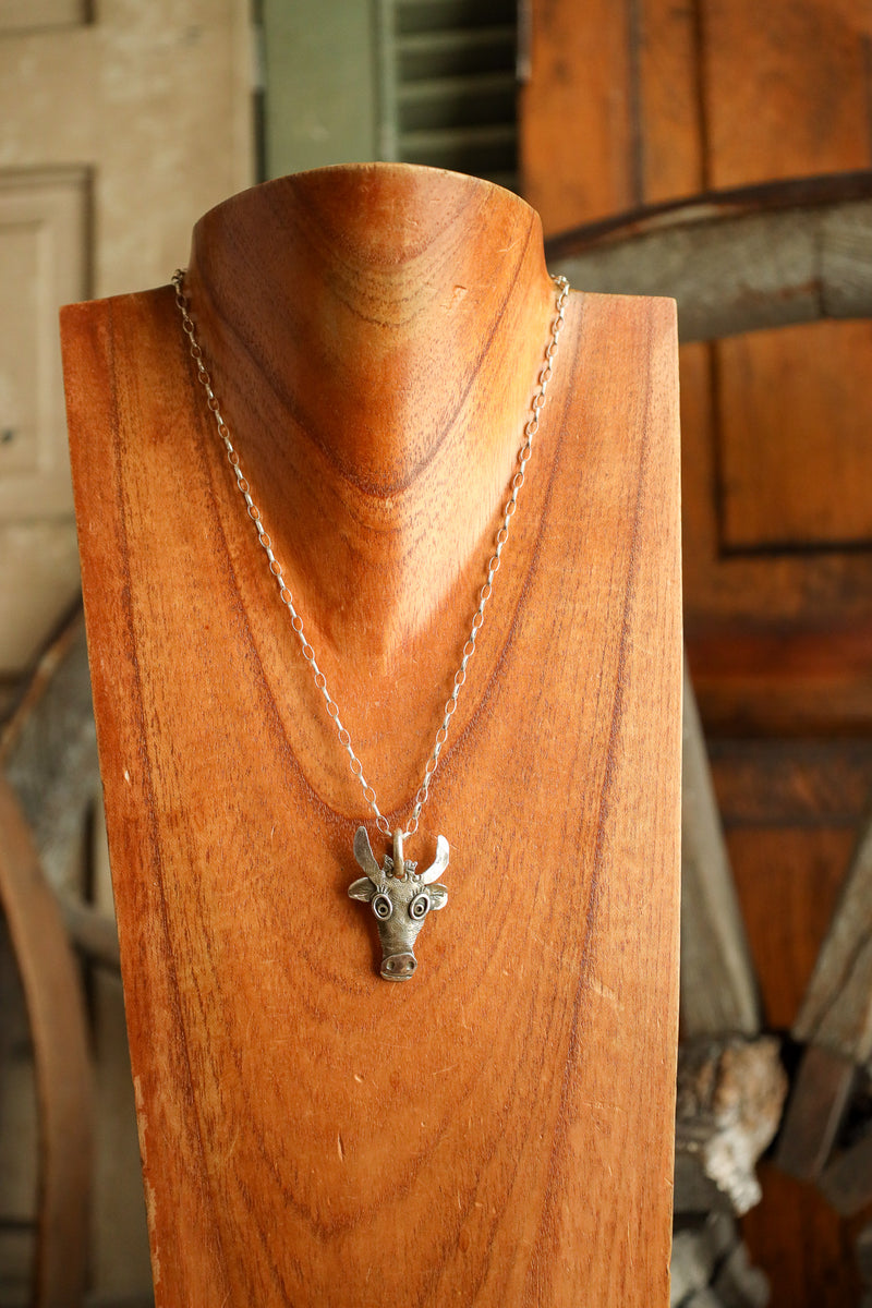 Necklace with a deer head pendant on a wooden stand.