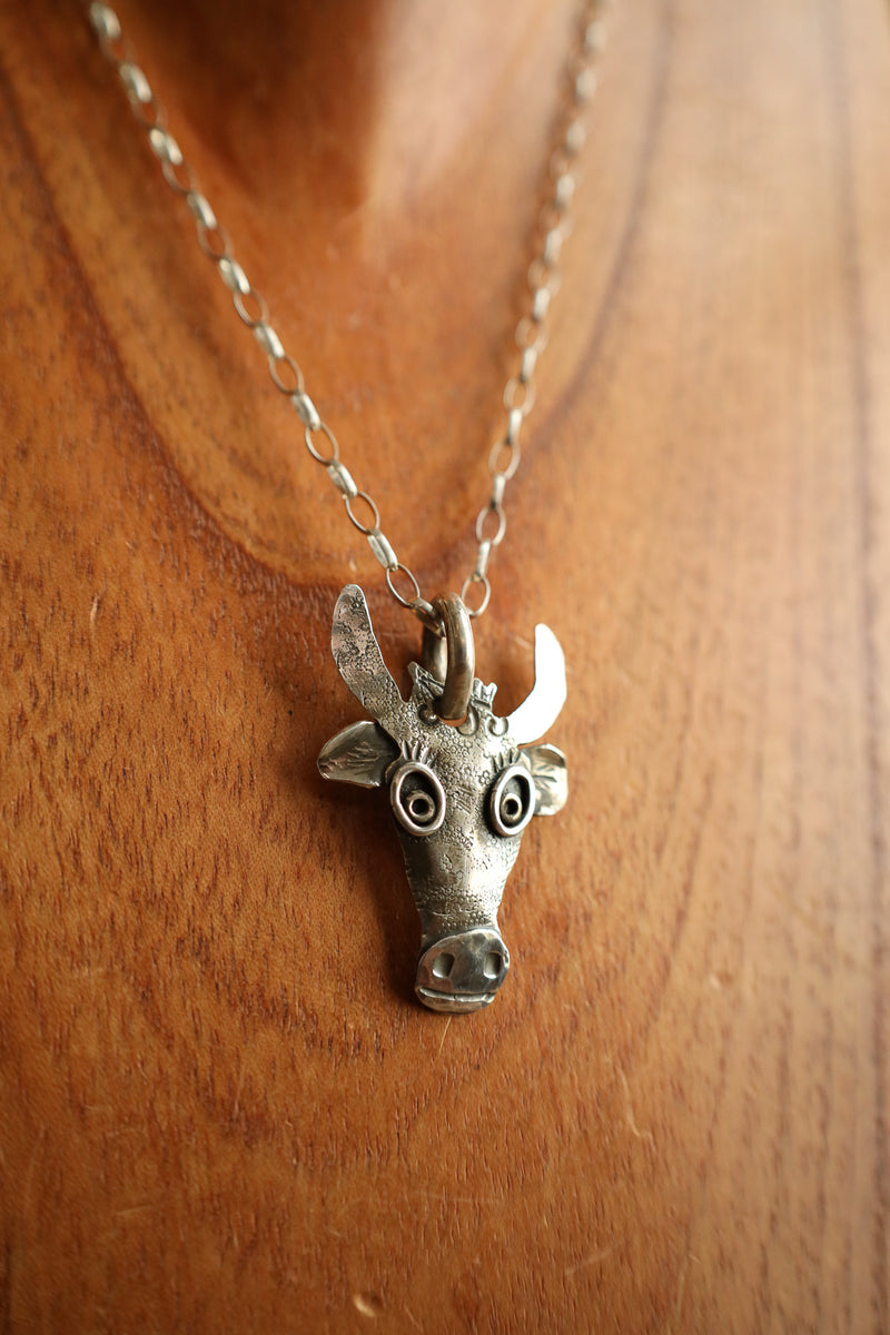 Silver bull head pendant necklace on a wooden background