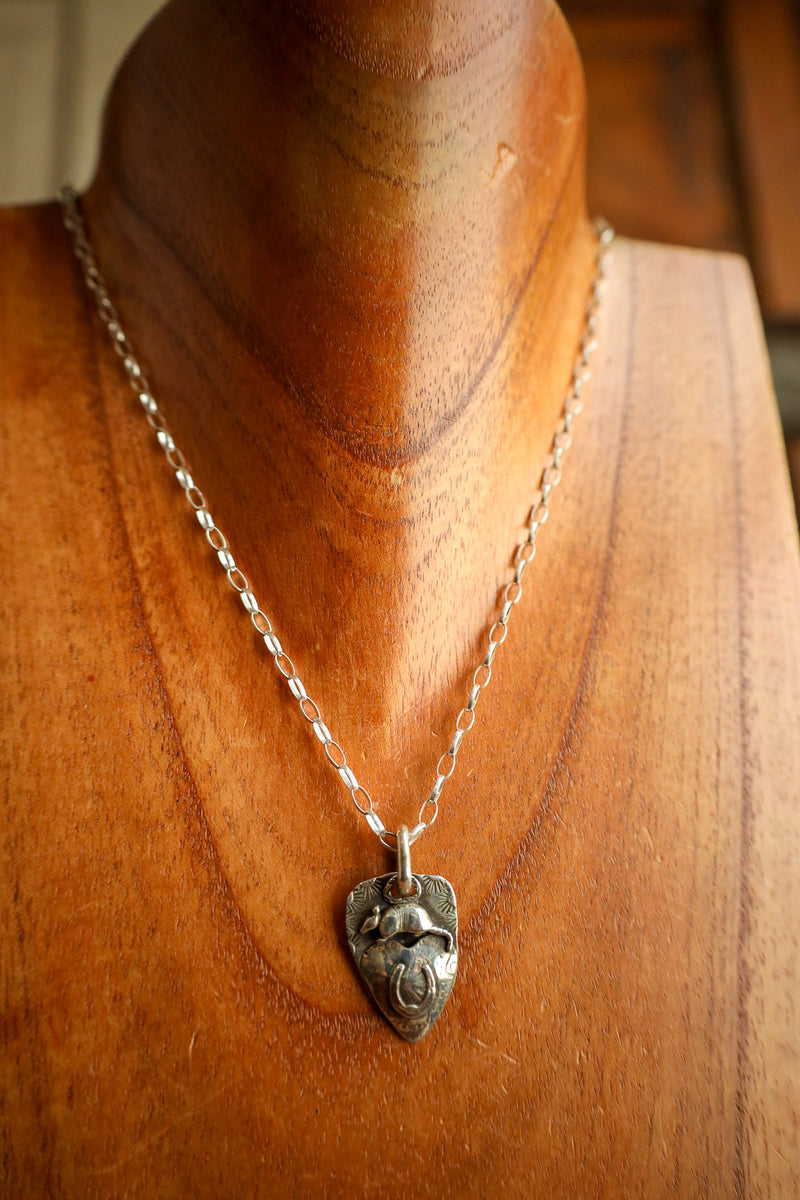 Silver necklace with a pendant on a wooden mannequin