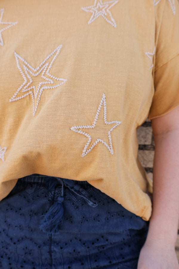 Woman wearing yellow t-shirt with embroidered cream stars all over