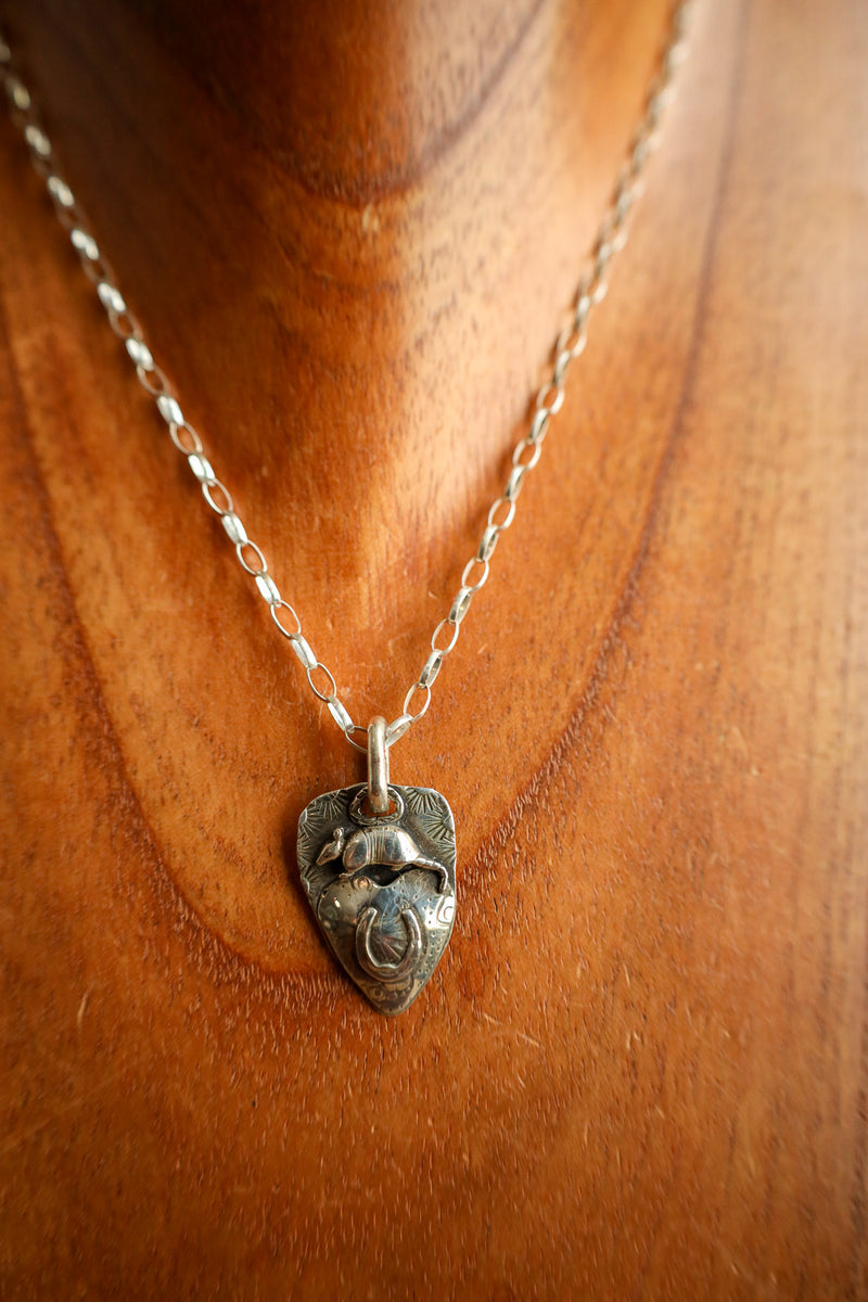 Silver necklace with a unique pendant on a wooden surface
