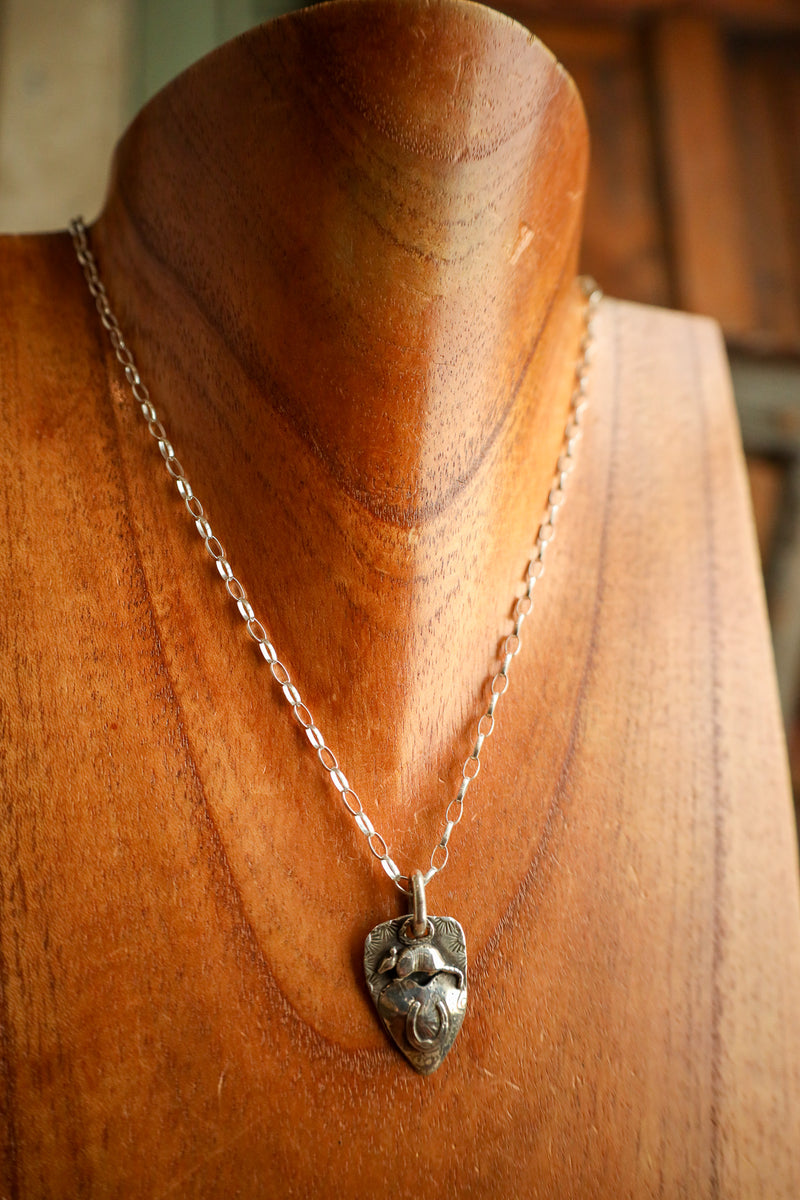Silver necklace with a pendant on a wooden mannequin