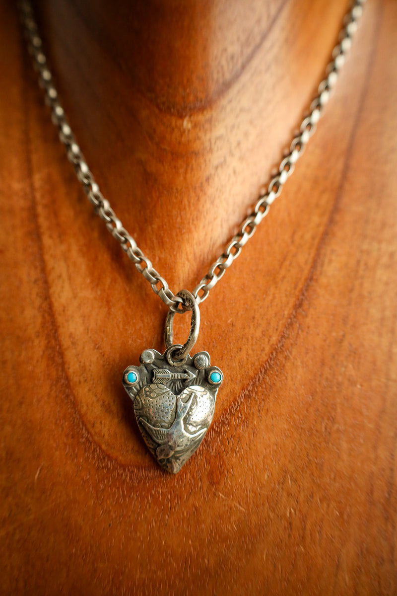 Silver necklace with a heart-shaped pendant on a wooden surface