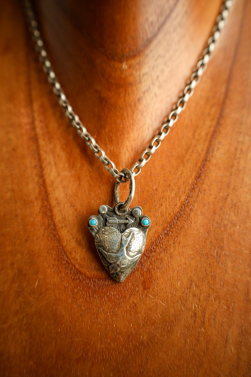 Silver necklace with a heart-shaped pendant on a wooden surface
