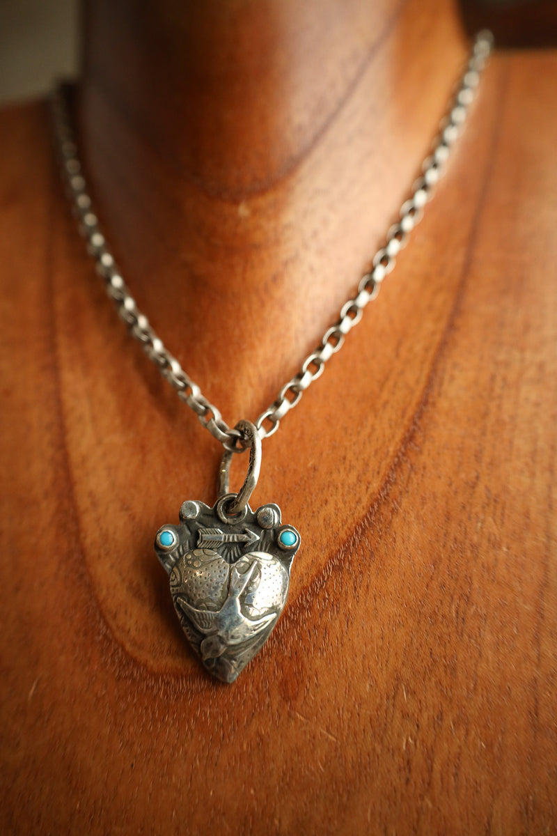 Silver necklace with a heart-shaped pendant on a wooden surface