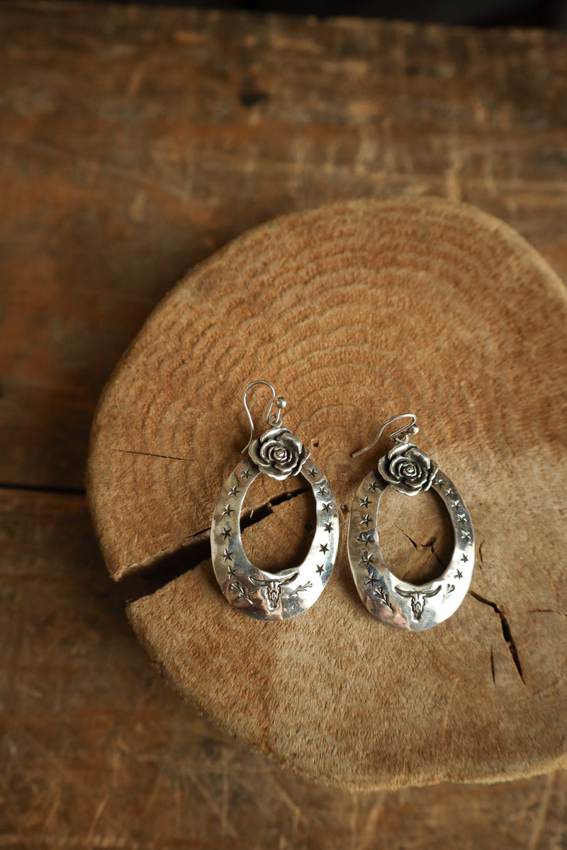 Silver earrings on a wooden surface