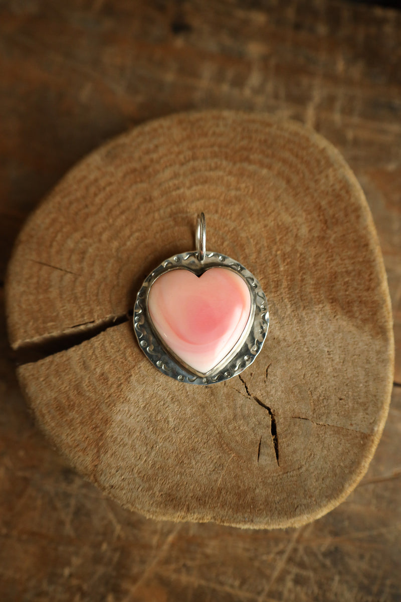 Heart-shaped pink pendant on a wooden surface