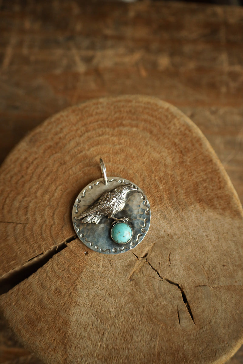 Silver pendant with turquoise stone on a wooden surface