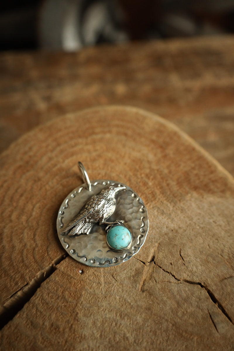 Silver pendant with turquoise stone on a wooden surface