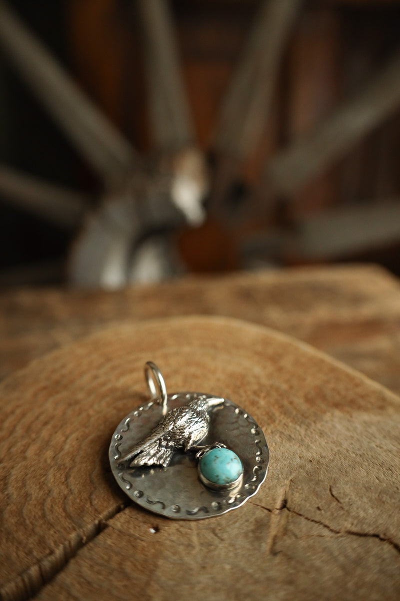 Silver pendant with turquoise stone on a wooden surface