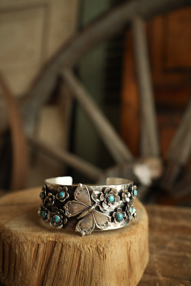 Silver bracelet with turquoise stones on a wooden block with a blurred background