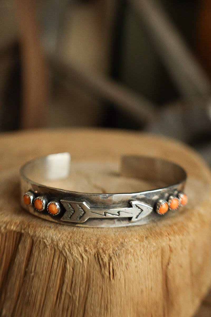Silver bracelet with orange stones on a wooden surface
