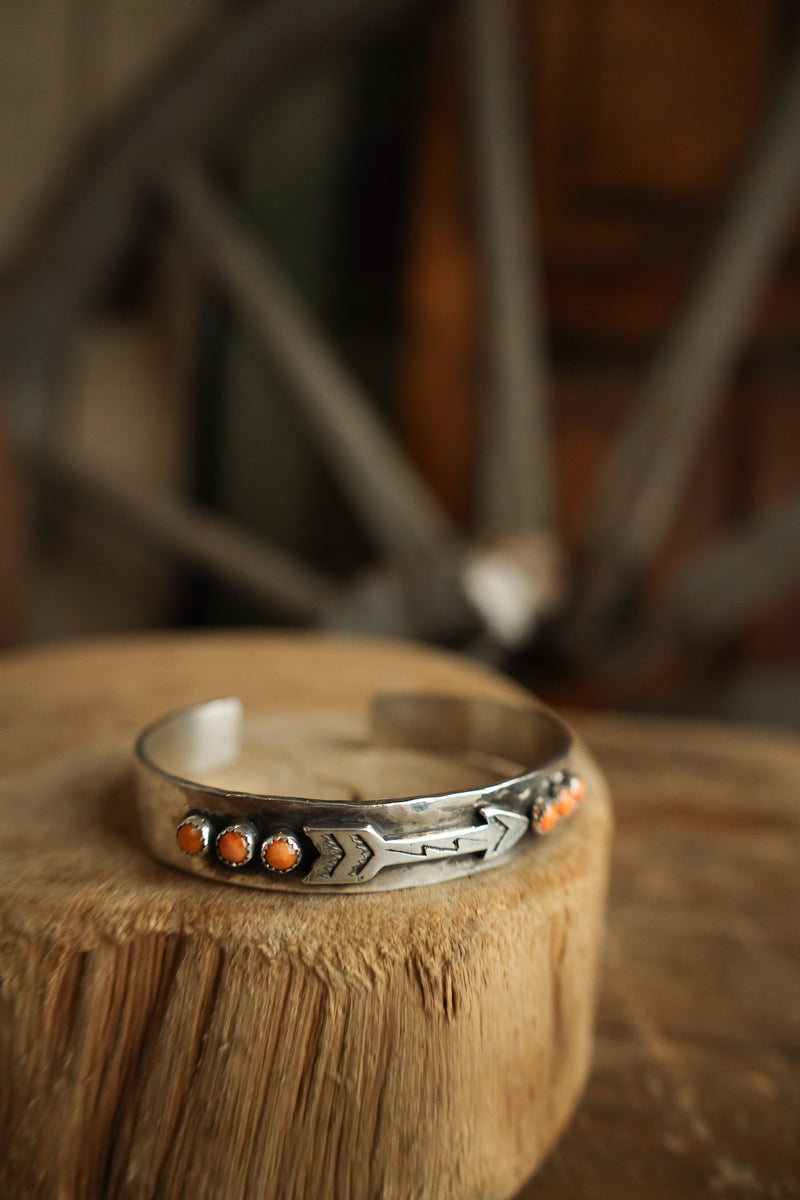 Silver bracelet with orange stones on a wooden surface