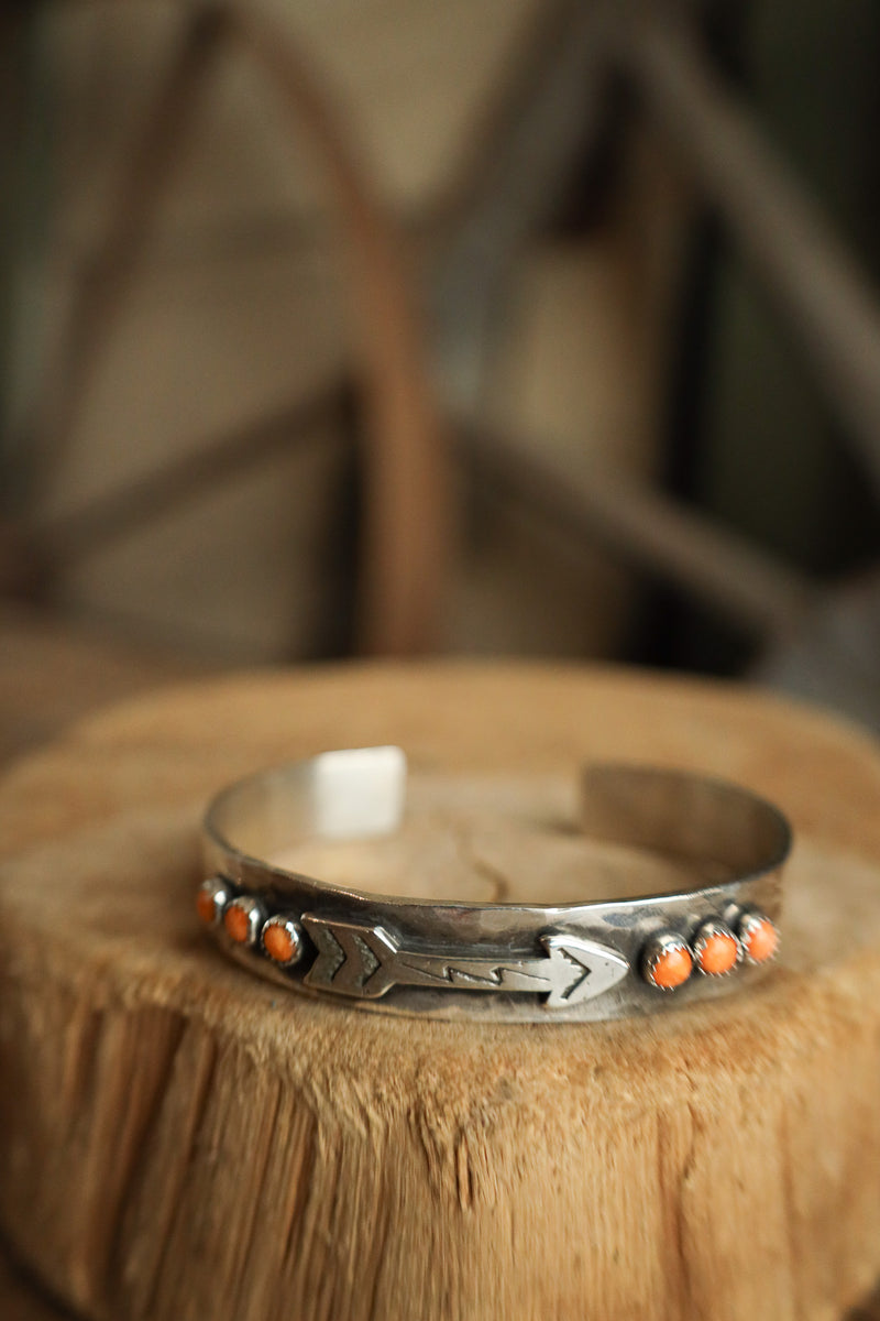 Silver bracelet with orange stones on a wooden surface