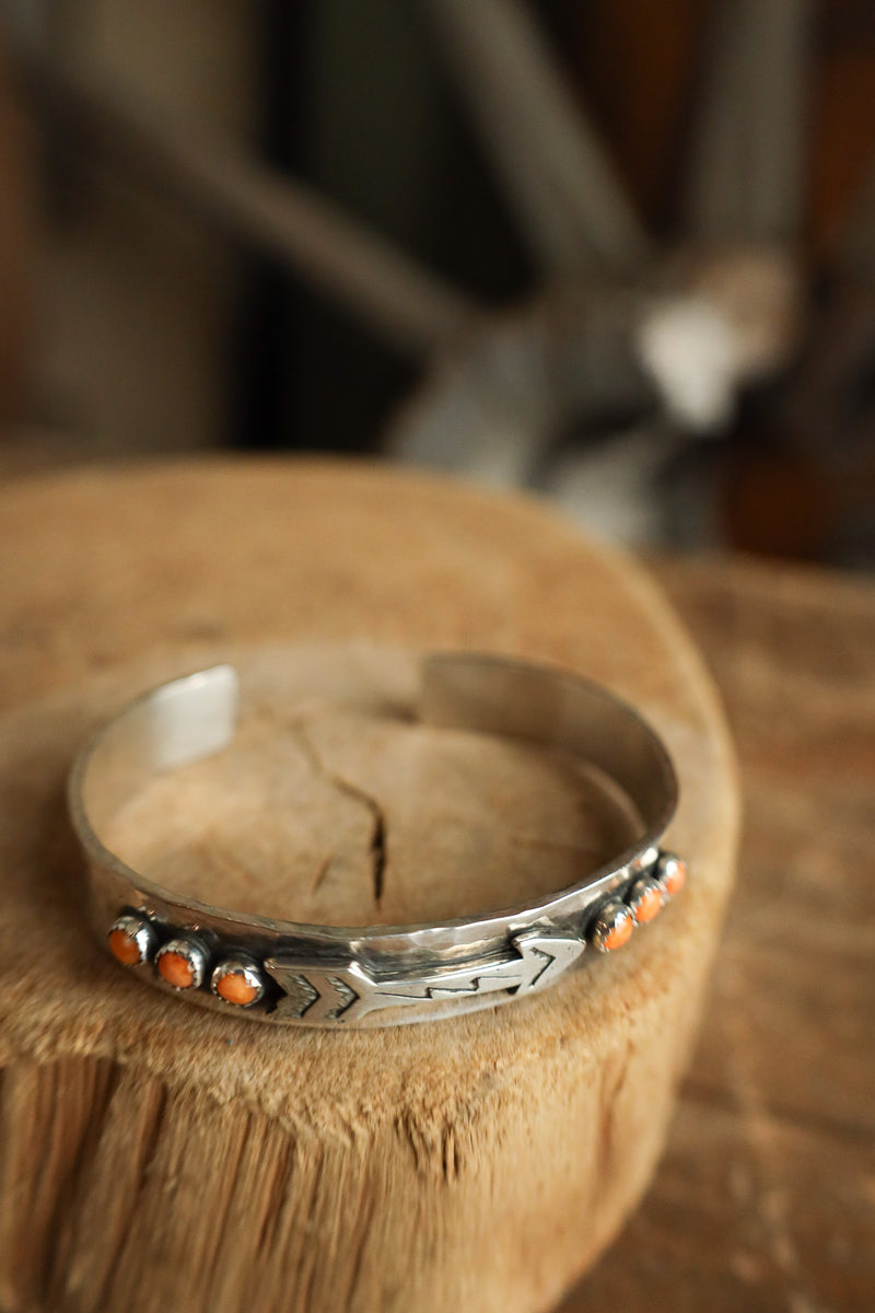 Silver ring with orange stones on a wooden surface with blurred antlers in the background