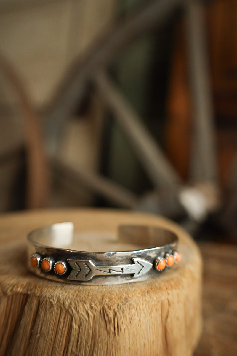 Silver bracelet with orange stones on a wooden surface