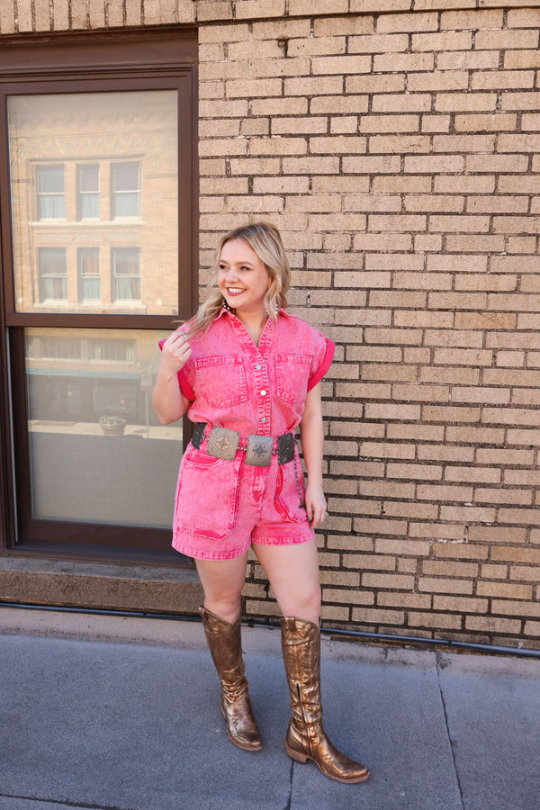 Woman wearing playful pink denim romper features a button front, easy-access zipper, and oversized pockets for convenience.