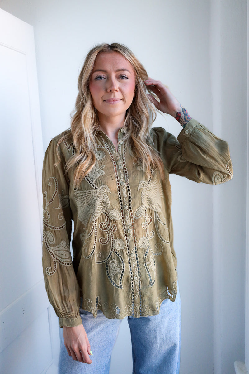 Woman wearing a beige embroidered blouse against a white background