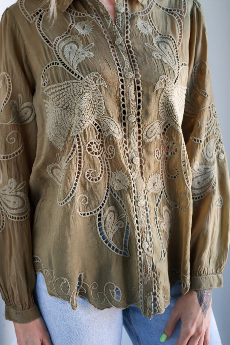 Brown embroidered blouse with intricate patterns on a plain background