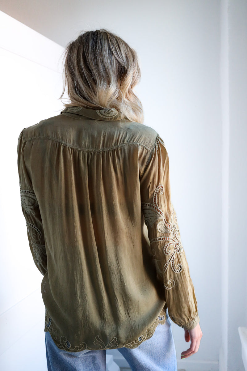 Person wearing a beige blouse with lace details on a white background